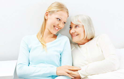 caregiver and elderly woman smiling to each other